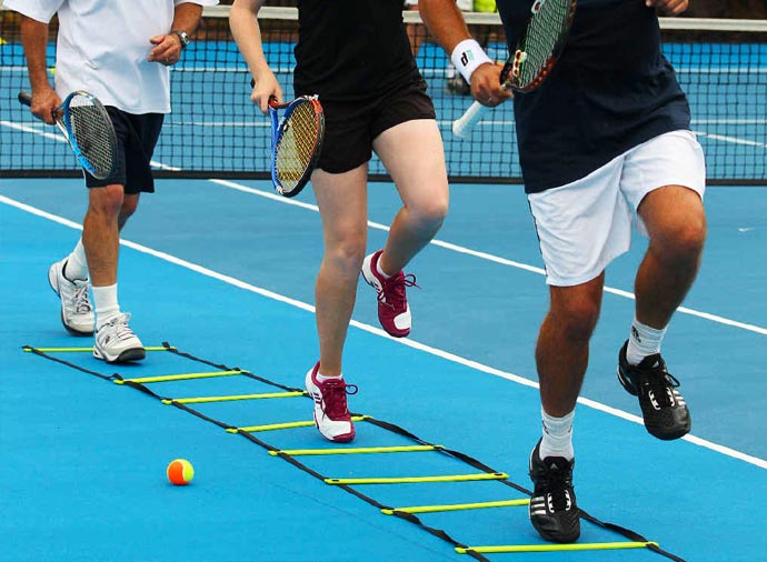 People running on a tennis court while holding racquets